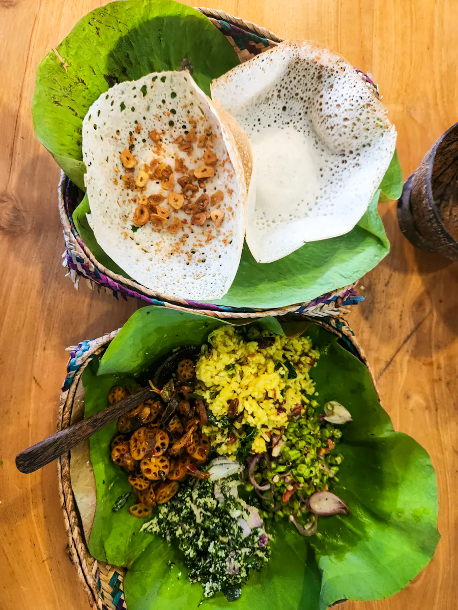 Hoppers and string hoppers on banana leaves with sambols and curry